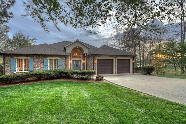 single story home featuring brick siding, a front yard, roof with shingles, a garage, and driveway