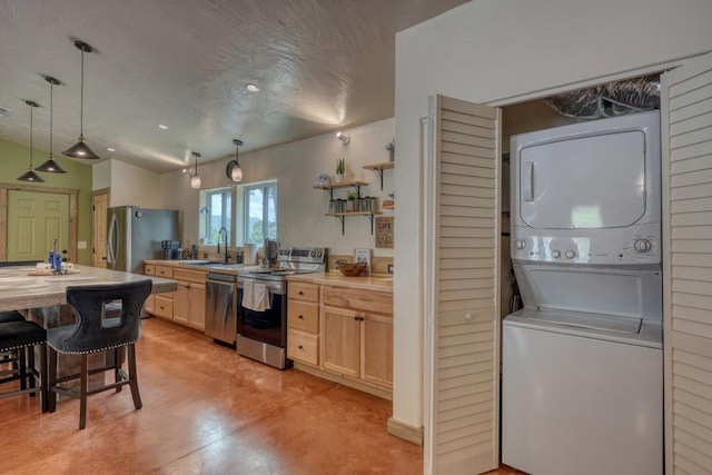 1529 Cedar View Ln, Hiawassee, GA 30546 - kitchen with stainless steel appliances, stacked washing machine and dryer, light brown cabinetry, pendant lighting, and concrete floors