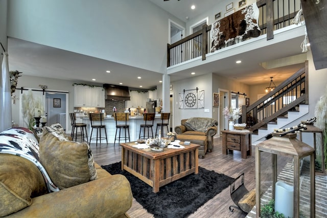 living room featuring hardwood / wood-style flooring, a barn door, and a high ceiling