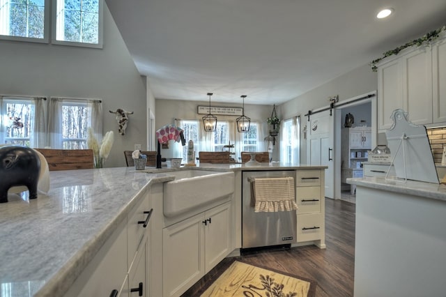 kitchen with decorative light fixtures, white cabinetry, dishwashing machine, light stone counters, and a barn door