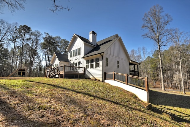 back of property with a wooden deck and a lawn