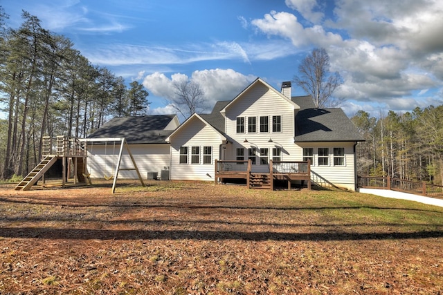 rear view of house featuring cooling unit, a deck, and a lawn