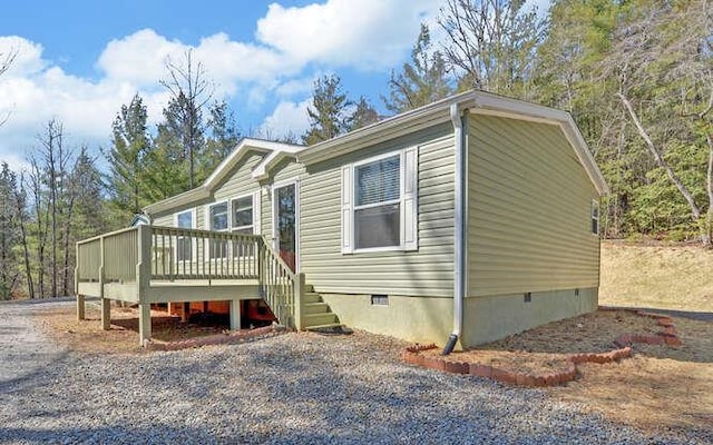 view of front of home featuring driveway, crawl space, and a wooden deck