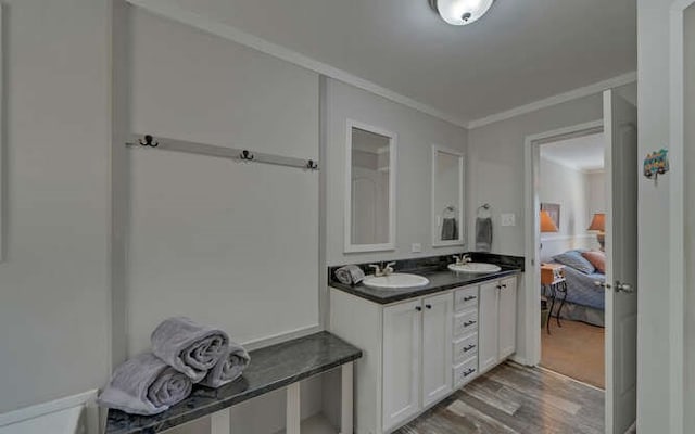 full bathroom featuring ornamental molding, double vanity, wood finished floors, and a sink