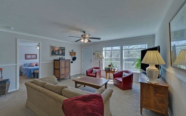 carpeted living area with ornamental molding and a ceiling fan