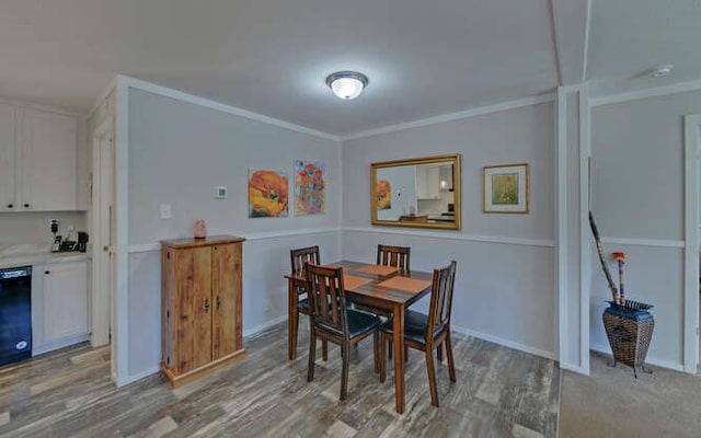 dining room with light wood-style floors, baseboards, and crown molding