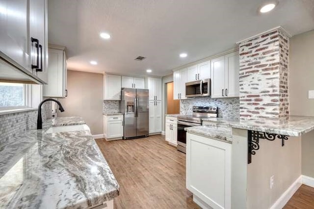 kitchen with white cabinetry, sink, light stone countertops, and appliances with stainless steel finishes