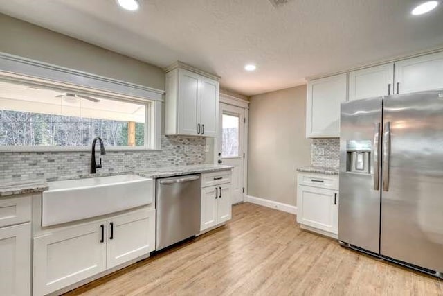 kitchen featuring white cabinets, appliances with stainless steel finishes, light hardwood / wood-style flooring, and sink