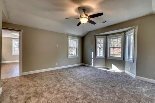 empty room with carpet flooring, vaulted ceiling, and ceiling fan