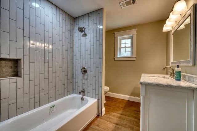 full bathroom with hardwood / wood-style floors, vanity, toilet, and tiled shower / bath