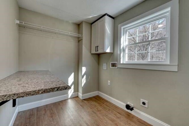 laundry area featuring electric dryer hookup, cabinets, light hardwood / wood-style flooring, and washer hookup