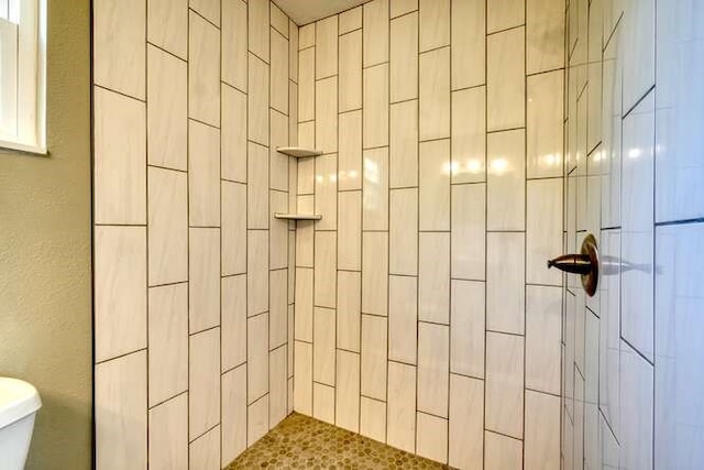 bathroom featuring a tile shower and toilet