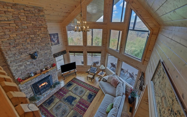 unfurnished living room featuring wood walls, an inviting chandelier, hardwood / wood-style flooring, a fireplace, and wood ceiling