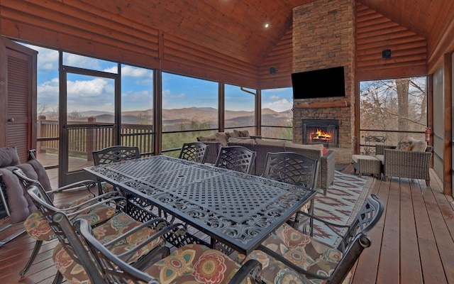 sunroom with an outdoor stone fireplace, plenty of natural light, and vaulted ceiling