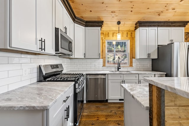 kitchen with sink, decorative light fixtures, stainless steel appliances, light stone counters, and dark hardwood / wood-style floors