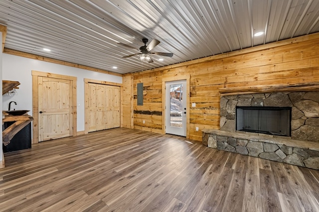 unfurnished living room featuring hardwood / wood-style floors, wood ceiling, a fireplace, wooden walls, and ceiling fan