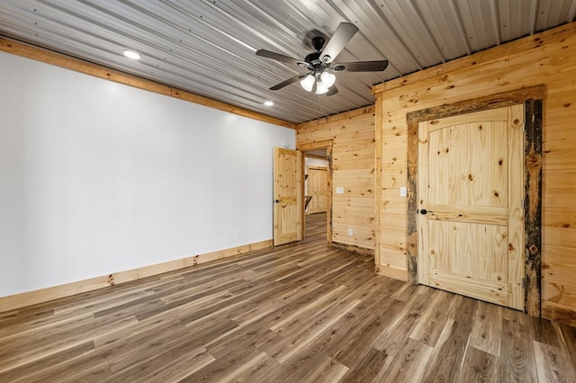 unfurnished bedroom featuring ceiling fan, hardwood / wood-style floors, and wooden walls