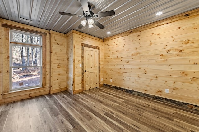 unfurnished room featuring ceiling fan, wood-type flooring, and wood walls