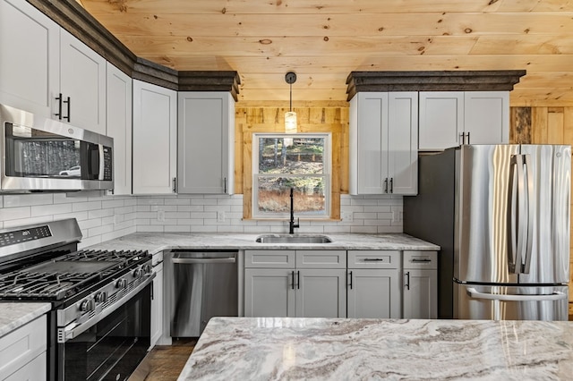 kitchen featuring pendant lighting, appliances with stainless steel finishes, sink, backsplash, and light stone counters