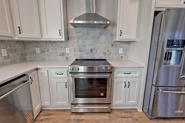 kitchen featuring wall chimney range hood, light countertops, stainless steel appliances, and wood finished floors