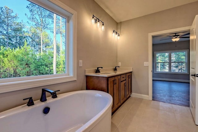 full bathroom featuring a sink, tile patterned floors, double vanity, baseboards, and a freestanding tub