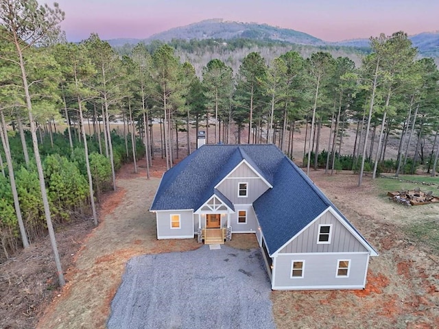 exterior space with gravel driveway, board and batten siding, a shingled roof, and a mountain view
