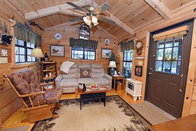 living room with wood walls, lofted ceiling with beams, light hardwood / wood-style floors, ceiling fan, and wooden ceiling