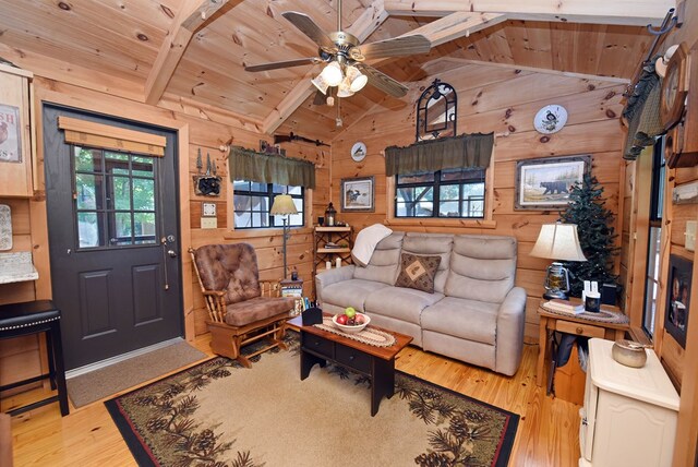 living room featuring light hardwood / wood-style flooring, ceiling fan, wooden ceiling, wood walls, and vaulted ceiling with beams