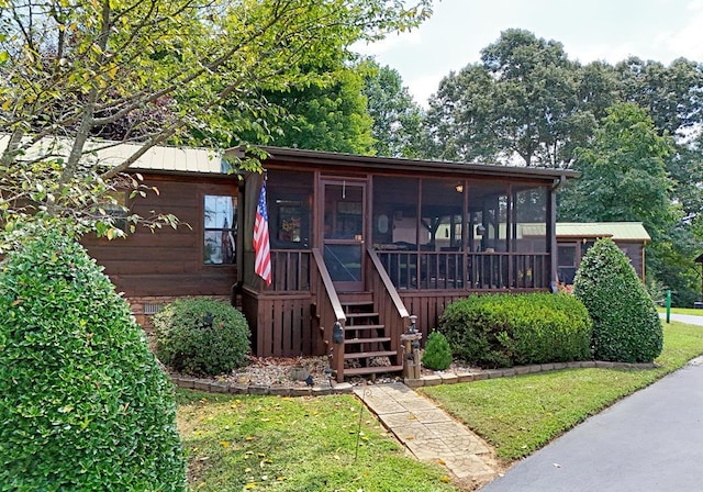 view of front of house featuring a sunroom and a front lawn