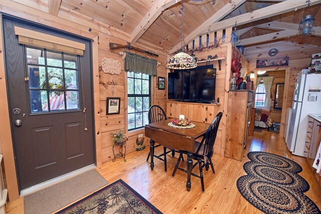 dining area featuring wooden ceiling, light hardwood / wood-style flooring, lofted ceiling with beams, and wooden walls