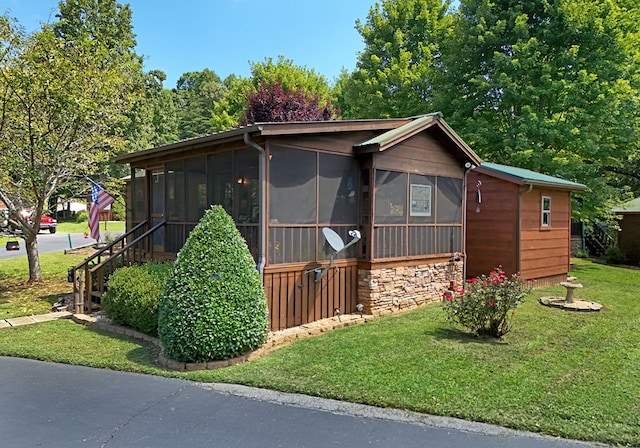 view of front of house featuring a sunroom and a front yard