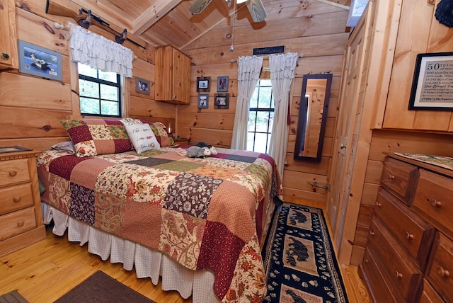 bedroom with lofted ceiling with beams, ceiling fan, wood walls, wooden ceiling, and light hardwood / wood-style flooring