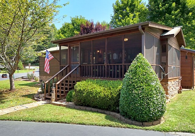 view of front of property featuring a sunroom and a front lawn