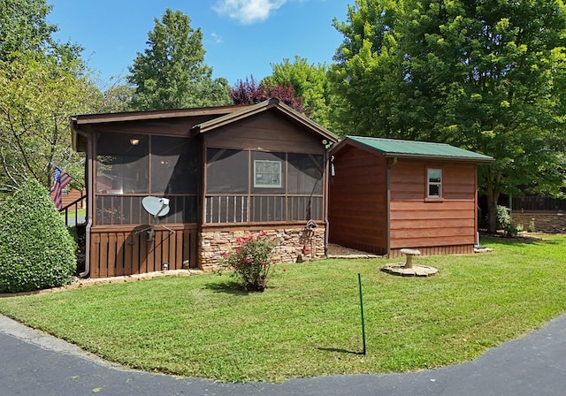 view of front facade featuring a sunroom, a front yard, and an outdoor structure