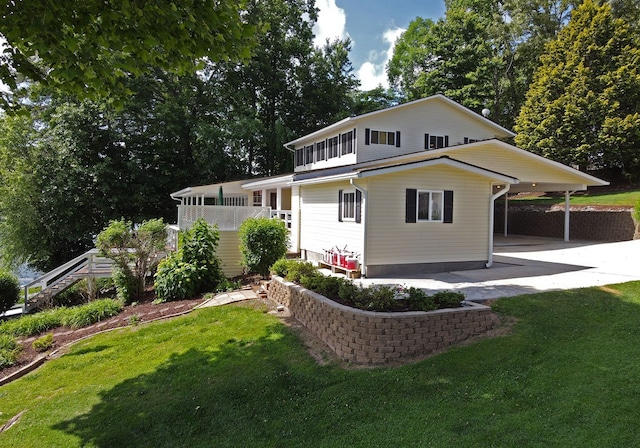 back of property with a carport, stairway, a lawn, and concrete driveway