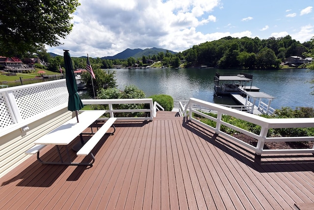 wooden terrace with a boat dock and a water and mountain view