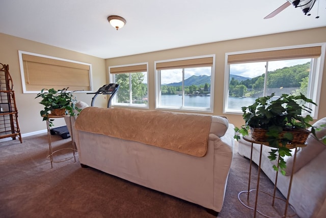 living area featuring carpet, baseboards, and ceiling fan