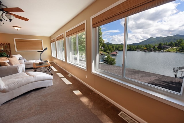 sunroom with a water and mountain view, baseboards, carpet, and visible vents