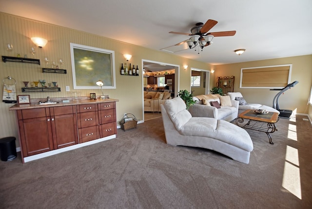 living room featuring carpet flooring, baseboards, and a ceiling fan