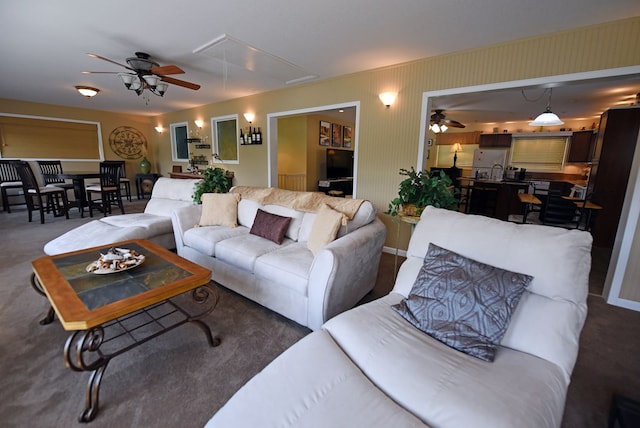 living area featuring attic access, ceiling fan, and carpet flooring