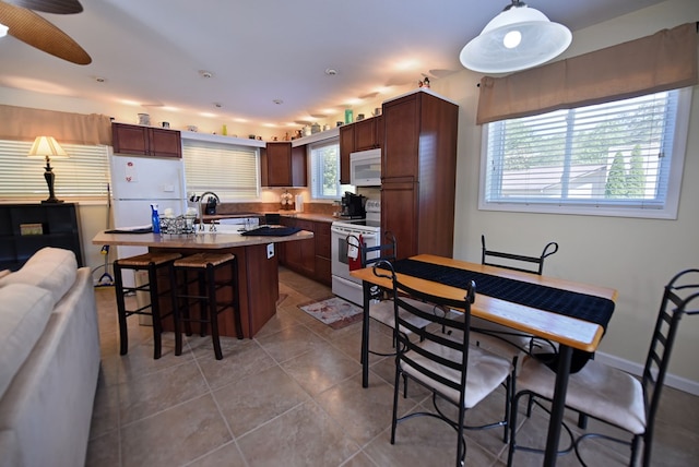 kitchen featuring a breakfast bar, white appliances, tile patterned flooring, and a kitchen island