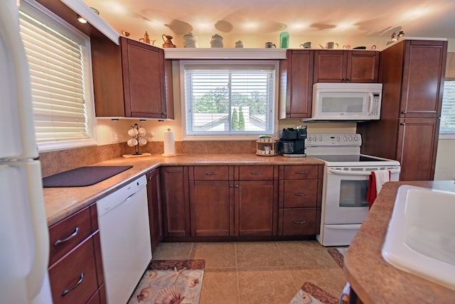 kitchen with white appliances, light countertops, a sink, and light tile patterned floors