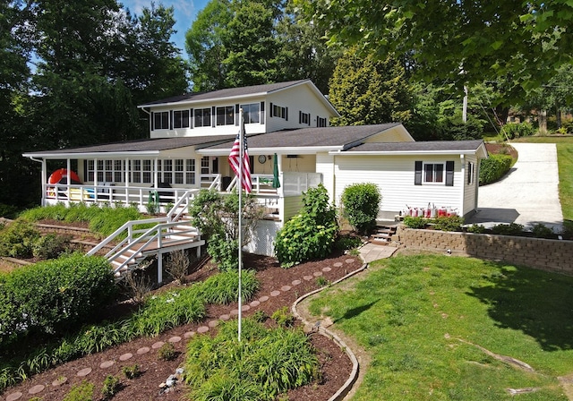 rear view of property with a yard, stairway, and a sunroom