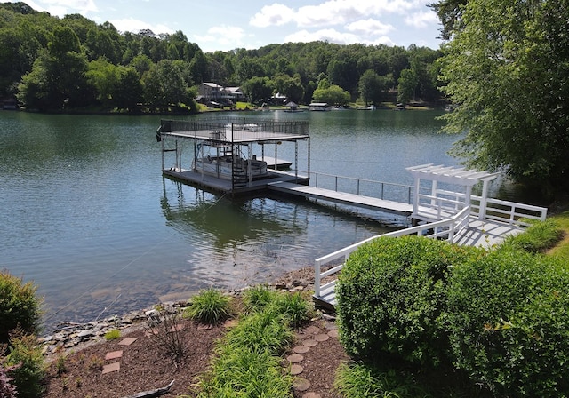 dock area featuring a water view, a wooded view, and boat lift