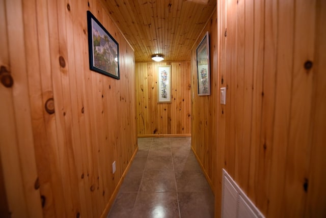 hall with wood walls, baseboards, wooden ceiling, and tile patterned flooring