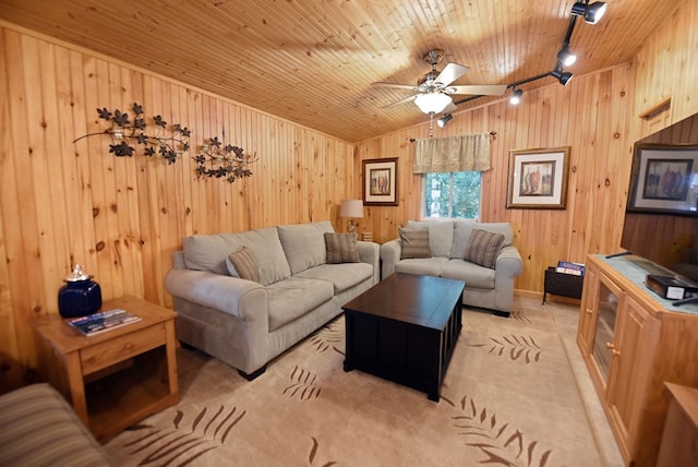 living room with ceiling fan, vaulted ceiling, wood walls, rail lighting, and light carpet