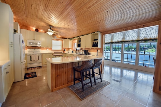 kitchen with light tile patterned floors, white appliances, a peninsula, visible vents, and light countertops