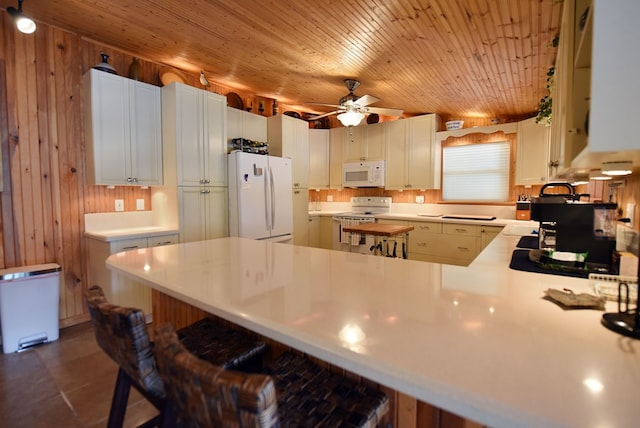 kitchen featuring white appliances, a peninsula, light countertops, a breakfast bar area, and wooden ceiling
