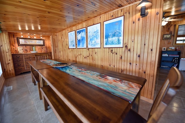 dining room with wooden walls, visible vents, baseboards, and wood ceiling