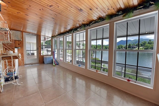 unfurnished sunroom with a water view, plenty of natural light, and tile patterned flooring
